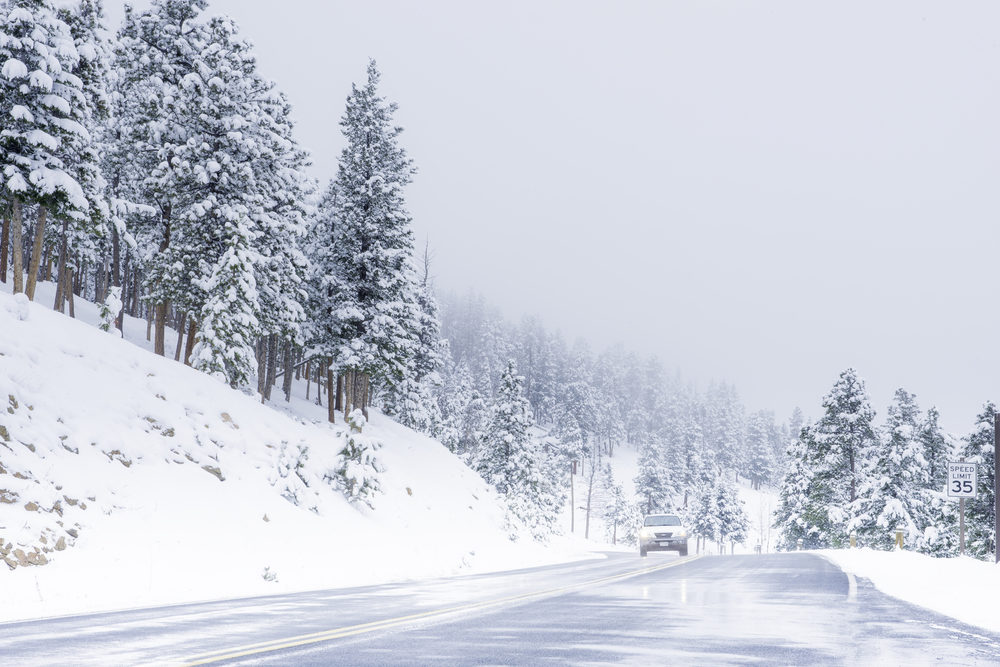 Beautiful winter scene with icy slick road driving situation curving road covered with snow and snowy trees all around